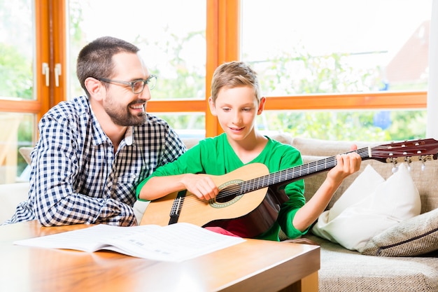 Padre e hijo tocando la guitarra en casa