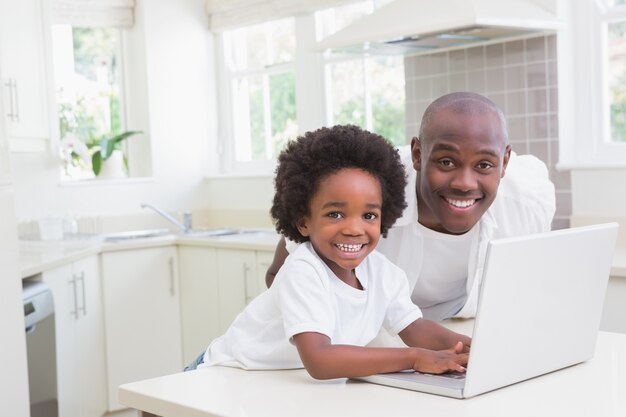 Padre e hijo usando la computadora portátil en el sofá