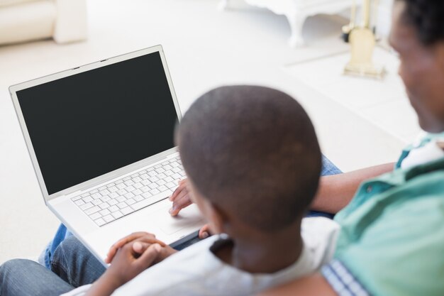 Padre e hijo usando la computadora portátil en el sofá