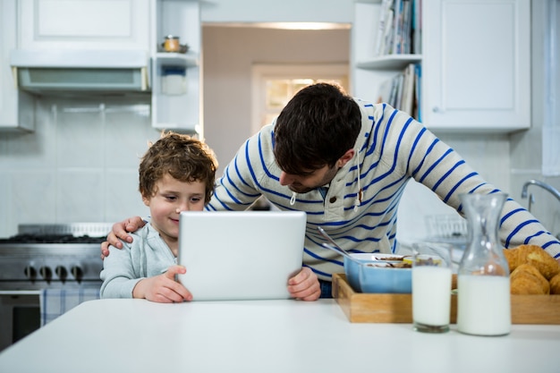 Padre e hijo usando tableta digital en la cocina