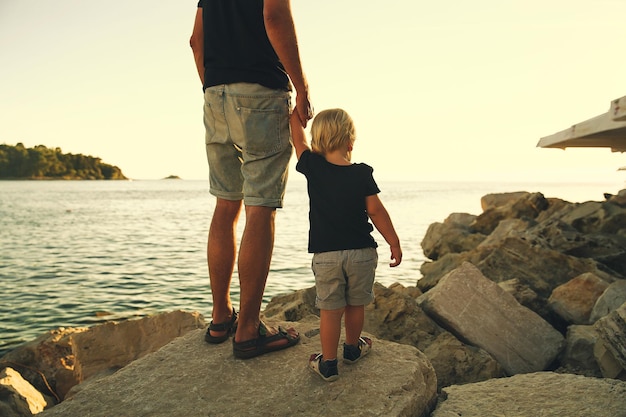 Padre e hijo vuelven siluetas caminando junto al mar Hombre y niño jugando juntos al aire libre en una playa de mar Familia amorosa y vacaciones de verano