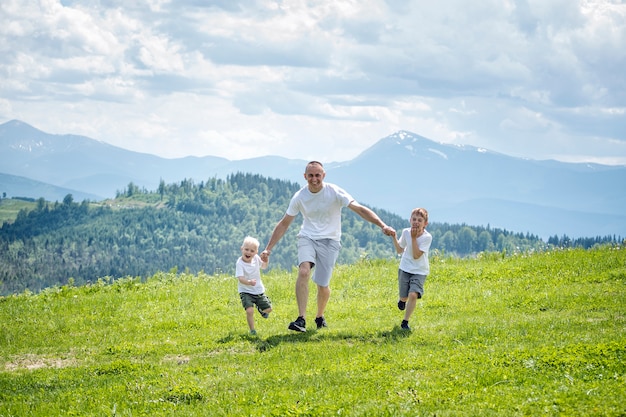 Padre e hijos corriendo en el campo verde