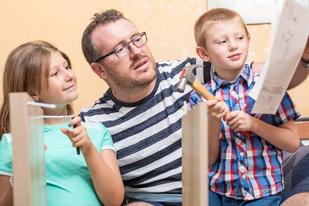 Padre e hijos están construyendo los muebles en casa.