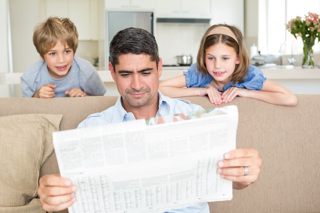 Padre e hijos leyendo periódico