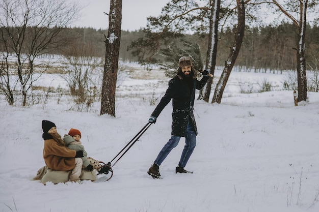 padre e hijos en un paseo en trineo por el bosque en busca de un árbol de Navidad