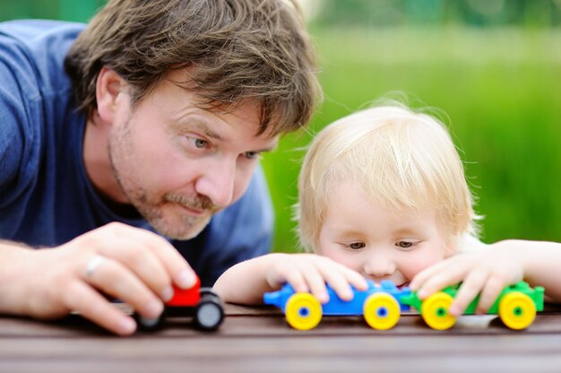 El padre de la Edad Media con su hijo del niño que juega con el juguete entrena al aire libre.