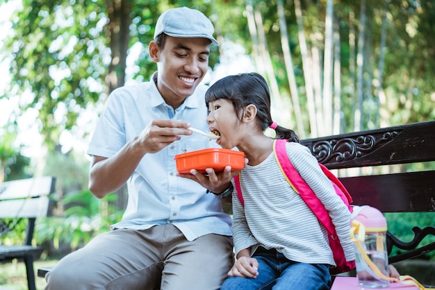 Padre encantador alimenta a su hija en el parque