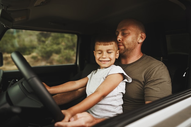 Padre enseña a su hijo pequeño a conducir en un viaje por carretera