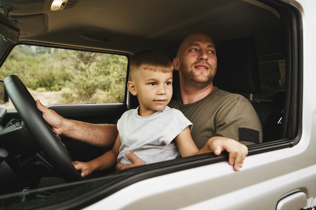 Padre enseña a su hijo pequeño a conducir en un viaje por carretera