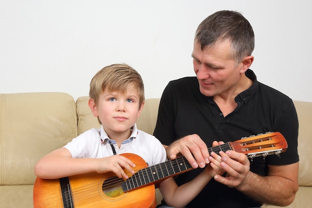 Padre enseña a su hijo a tocar la guitarra