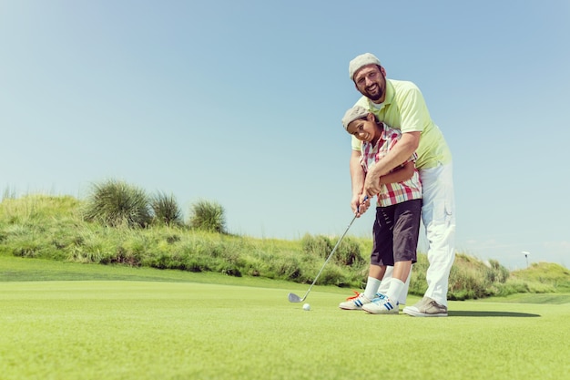 Padre enseñando hijo jugando al golf en el club