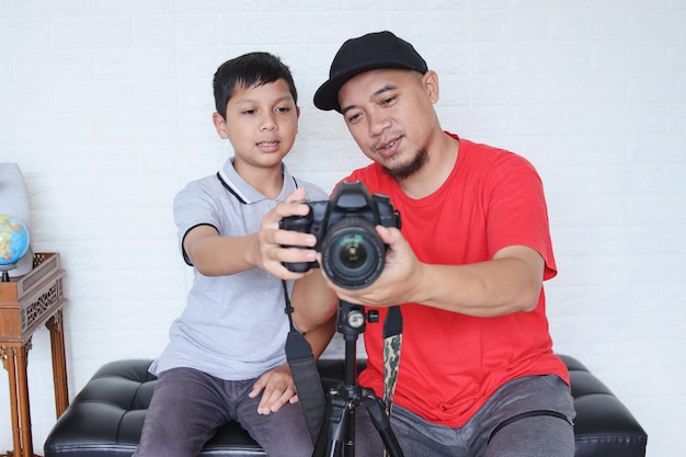 Padre enseñando a un lindo hijo pequeño a usar una cámara digital para fotografía