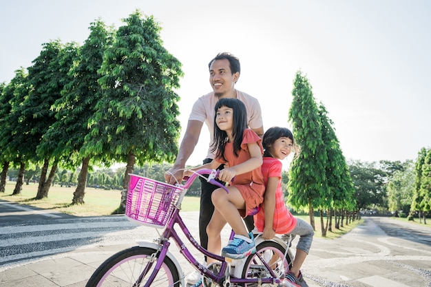 Padre enseñando a su hija a andar en bicicleta en el parque