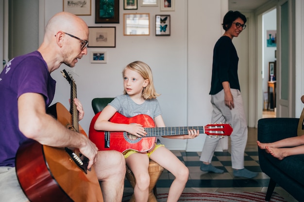 Padre enseñando a su hija a tocar la guitarra