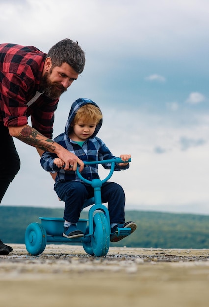 Foto padre enseñando a su hijo a andar en bicicleta el niño aprende a andar en bicicleta con su papá papá