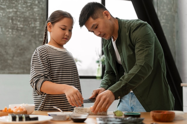 Foto padre enseñando a su hijo a hacer sushi