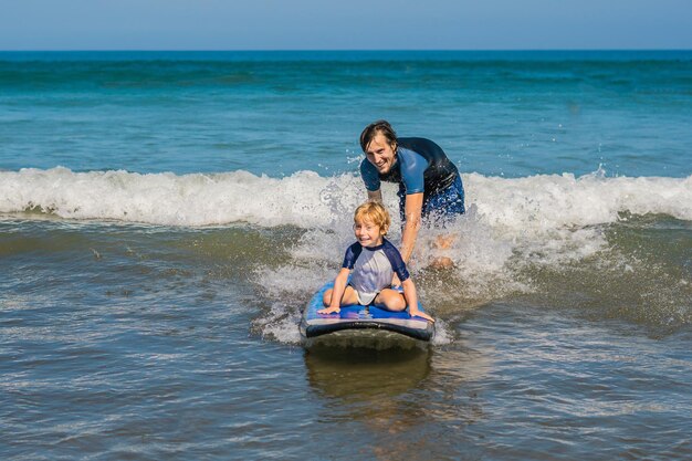 Padre enseñando a su hijo pequeño a surfear en el mar de vacaciones o vacaciones. Concepto de viajes y deportes con niños.