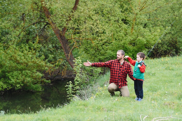 Un padre enseñando a su hijo a pescar en un río al aire libre bajo el sol de verano