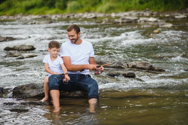 Padre enseñando a su hijo a pescar en el río.