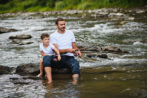 Padre enseñando a su hijo a pescar en el río.