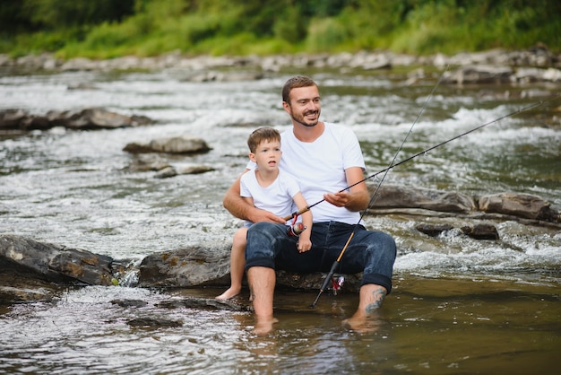 Padre enseñando a su hijo a pescar en el río.