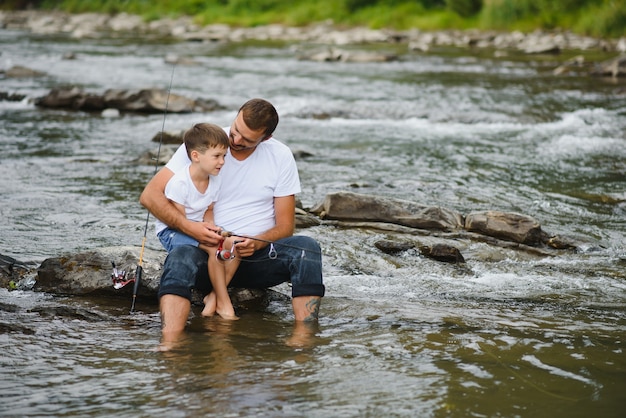 Padre enseñando a su hijo a pescar en el río.