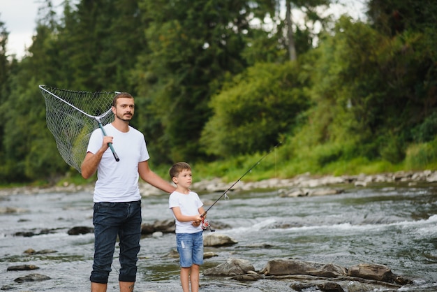 Padre enseñando a su hijo a pescar en el río.