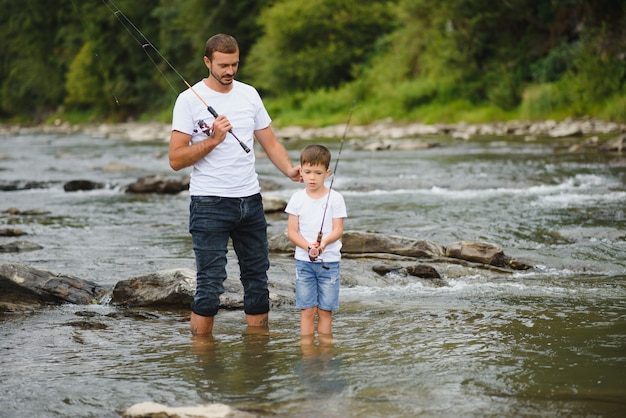 Padre enseñando a su hijo a pescar en el río.