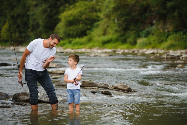 Padre enseñando a su hijo a pescar en el río.