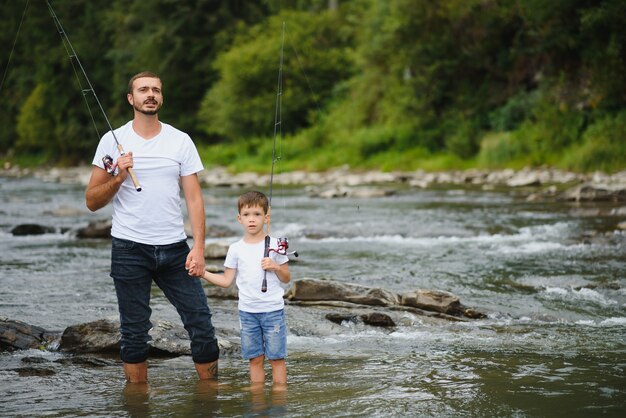 Padre enseñando a su hijo a pescar en el río.