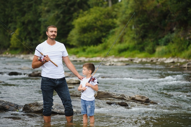 Padre enseñando a su hijo a pescar en el río.