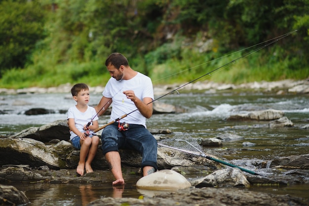 Padre enseñando a su hijo a pescar en el río.