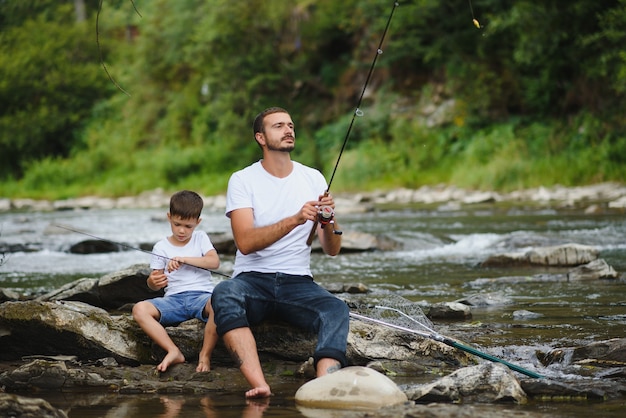 Padre enseñando a su hijo a pescar en el río.