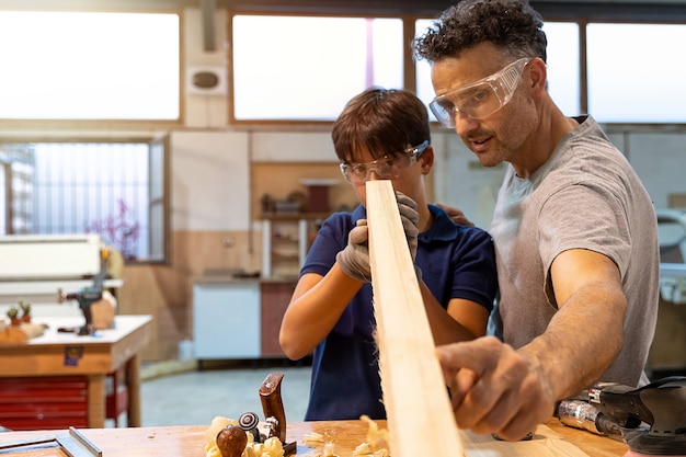 Padre enseñando a su hijo a trabajar con madera en una carpintería.