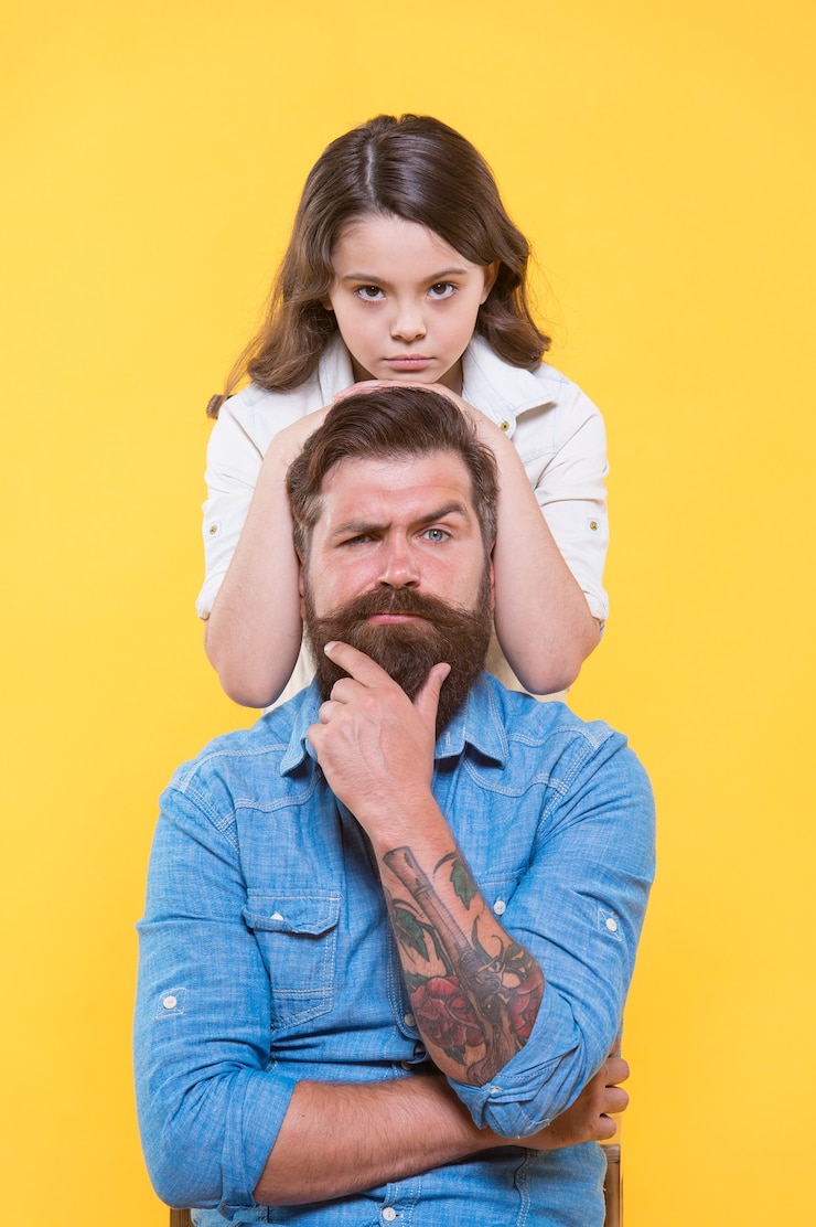 Foto el padre es el ídolo de cada hijo. hija pequeña abrazo padre serio. pequeña niña y padre fondo amarillo. dia del padre. valores familiares. papá, nunca nos separaremos.