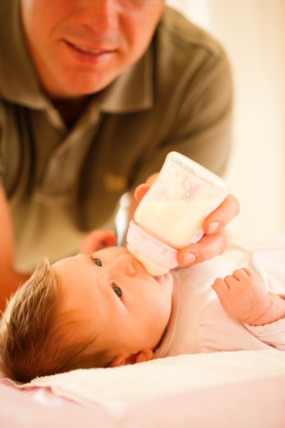 Padre está alimentando a su bebé con un biberón; escena muy tranquila