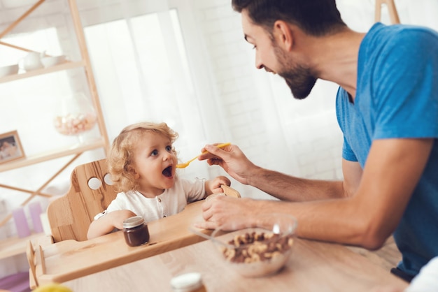 Padre está alimentando a su hijo un desayuno.