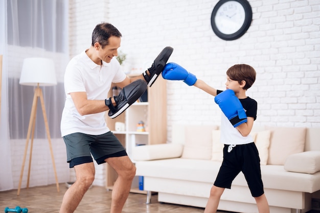 El padre está entrenando a su hijo boxeo.