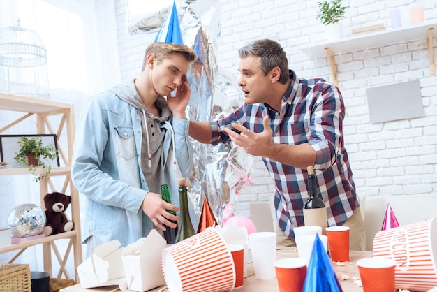 Padre está tratando de hacer que su hijo de resaca se levante.