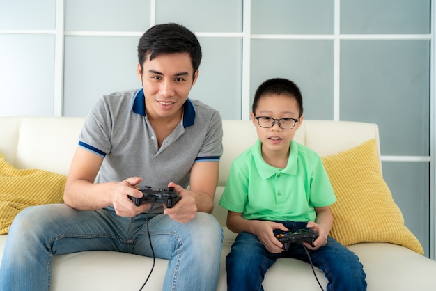 Padre de familia asiático y su hijo a jugar videojuegos