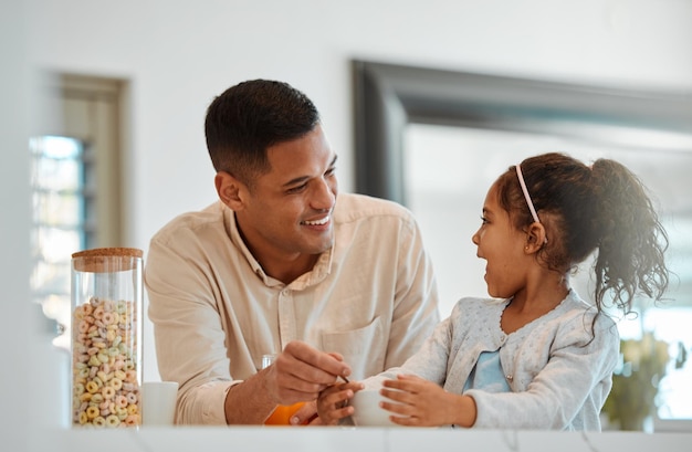 Padre de familia feliz e hijo desayunando y hablando del desarrollo del crecimiento escolar y la salud en el hogar Papá ayudando a un niño o una niña con cereales o comida matutina y una conversación divertida en la cocina