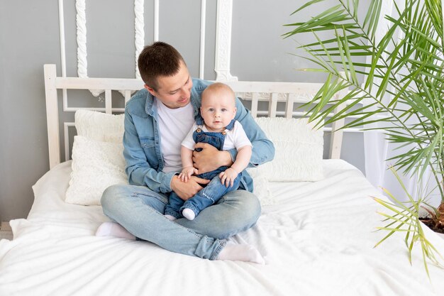 Padre de familia feliz sosteniendo a un bebé en la cama en casa Concepto del Día del Padre