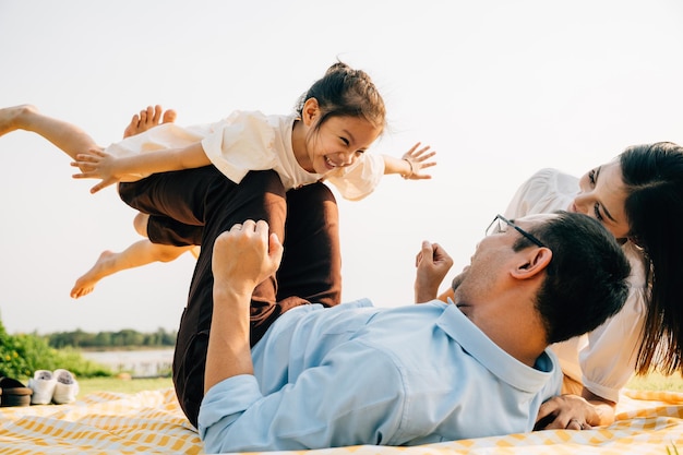 Padre de familia feliz sosteniendo a una hija pequeña en piernas rectas con madre