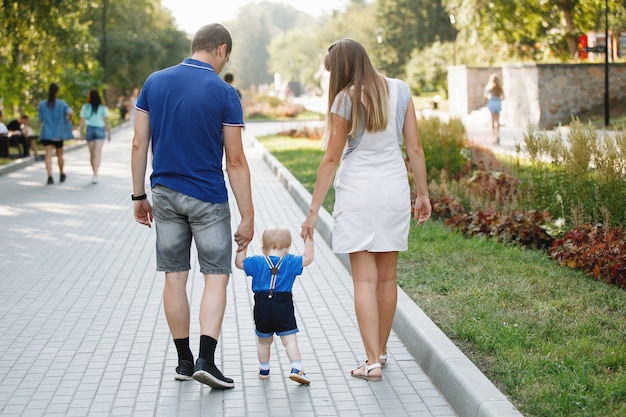 Padre de familia, mamá e hijo están caminando por la acera en el parque de la ciudad en verano