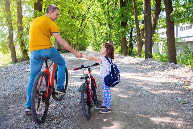 Padre feliz enseña a su hija a andar en bicicleta Familia pasando tiempo juntos