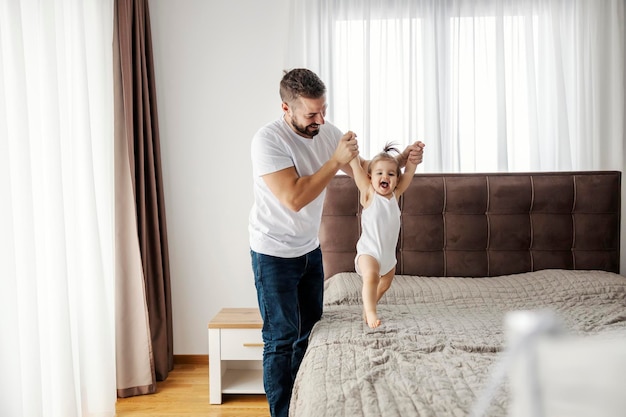 Un padre feliz le está enseñando a su bebé a caminar