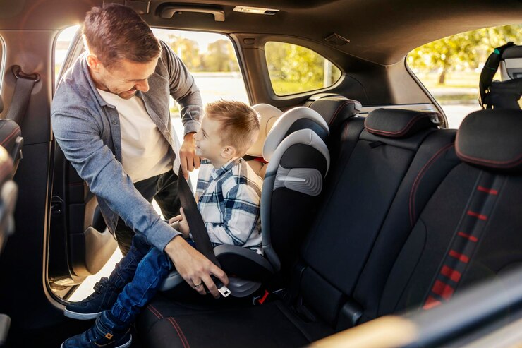Un padre feliz está poniendo a su hijo en su asiento de coche Se están preparando para el viaje