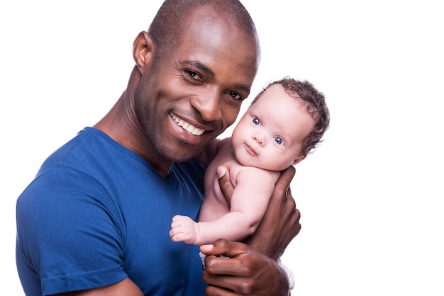 Padre feliz. Feliz joven africano sosteniendo a su pequeño bebé y sonriendo mientras está de pie aislado en blanco