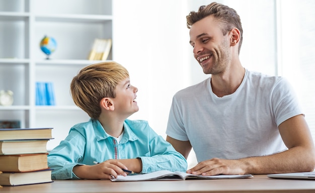 El padre feliz y un hijo haciendo los deberes en el escritorio