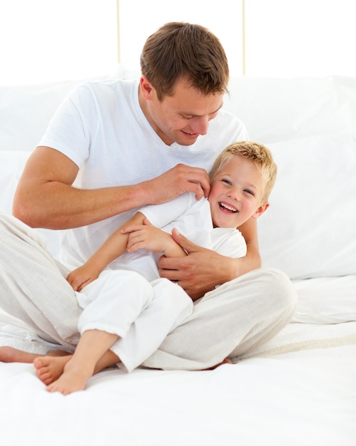 Padre feliz jugando con su niño en una cama